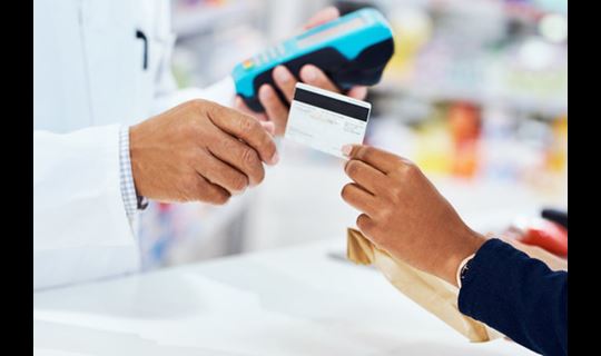 Hand giving copay card to pharmacist