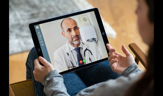 Male doctor speaking to patient on a tablet